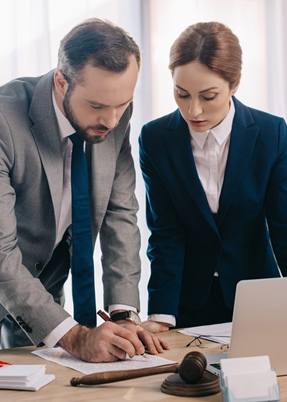 lawyers-in-suits-working-together-on-project-at-workplace-with-gavel-and-laptop-in-office
